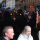 Protesters in the street reflected in the glass of a restaurant as onlookers stare out.